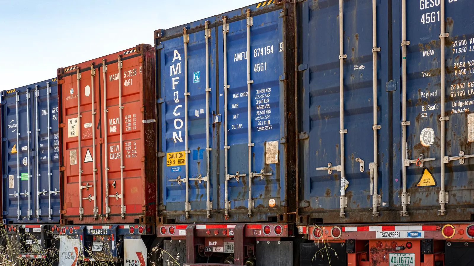 Stacked shipping containers inside a large industrial warehouse
