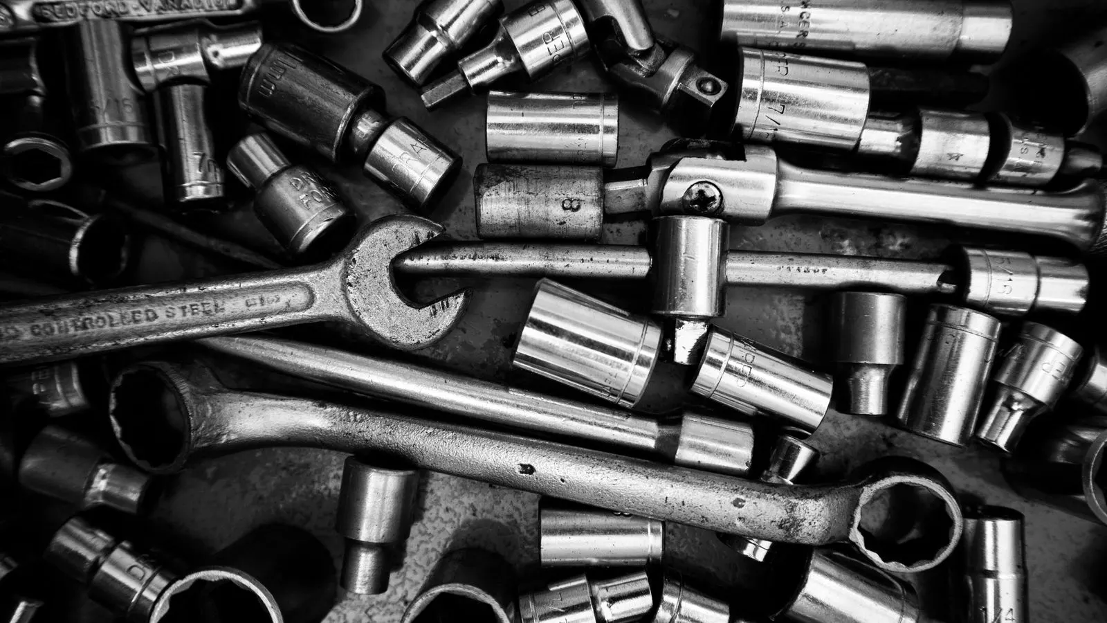 Close-up photograph of steel bolts and nuts arranged on a metal workbench.