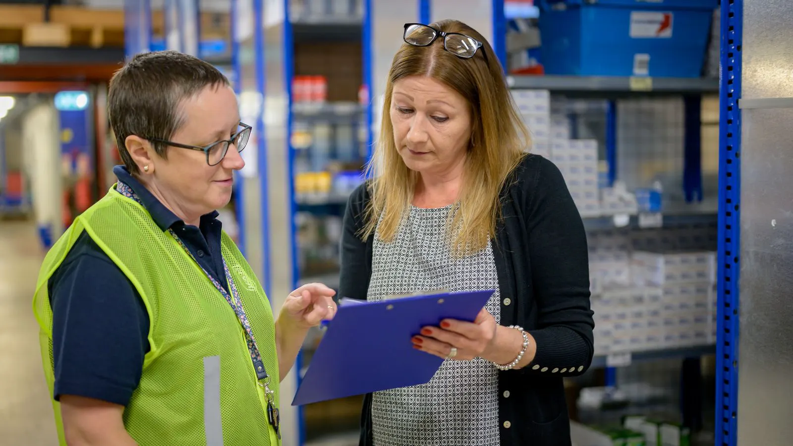 Inspector reviewing fastener boxes and supplier certification documents in a warehouse