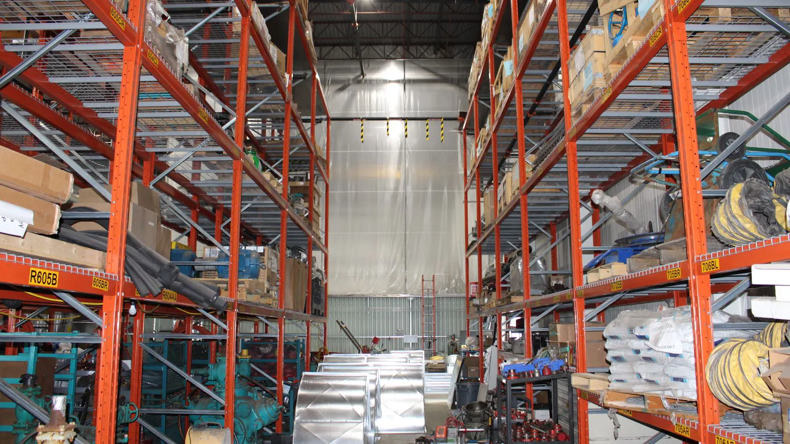 A worker checking inventory on a metal rack of bolts in a warehouse