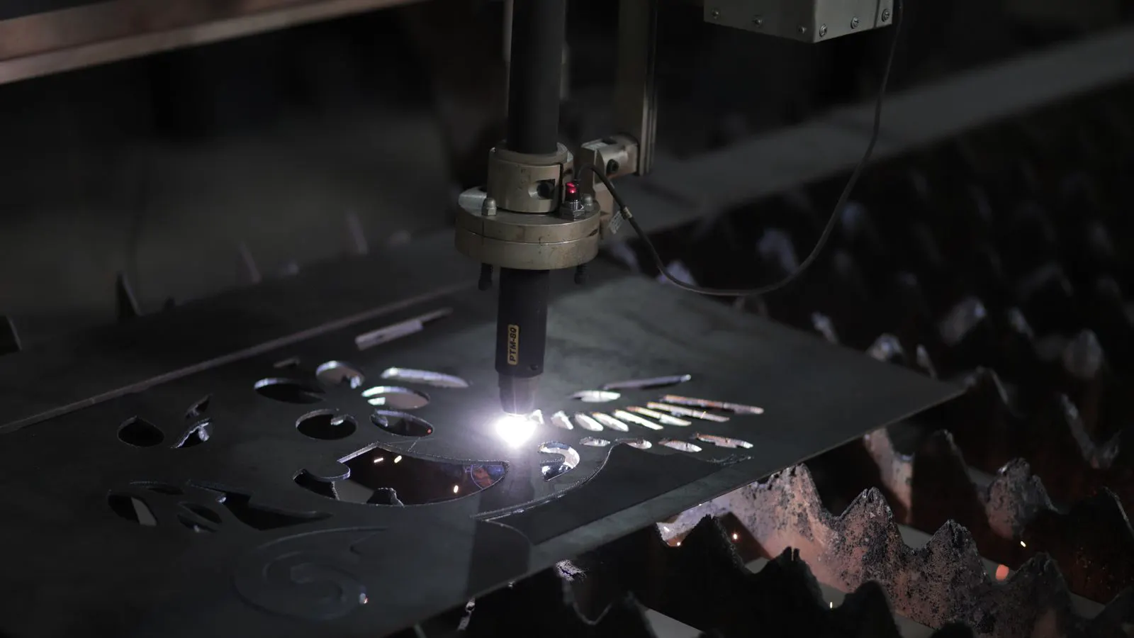 A professional laser welding setup processing a thin steel panel in a workshop.