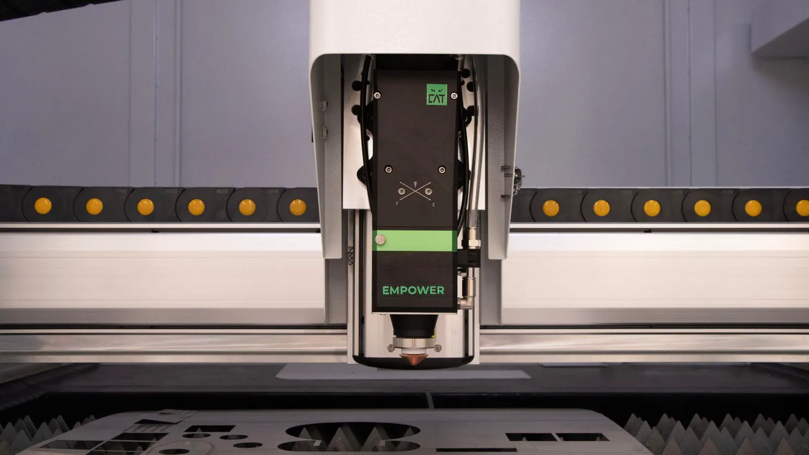 A metallic laser cutting head mounted on a machine gantry.