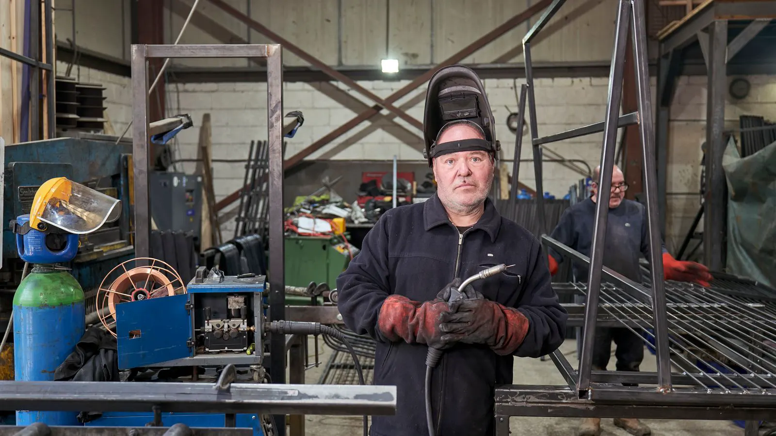 A technician inspecting a welding machine in an industrial workshop