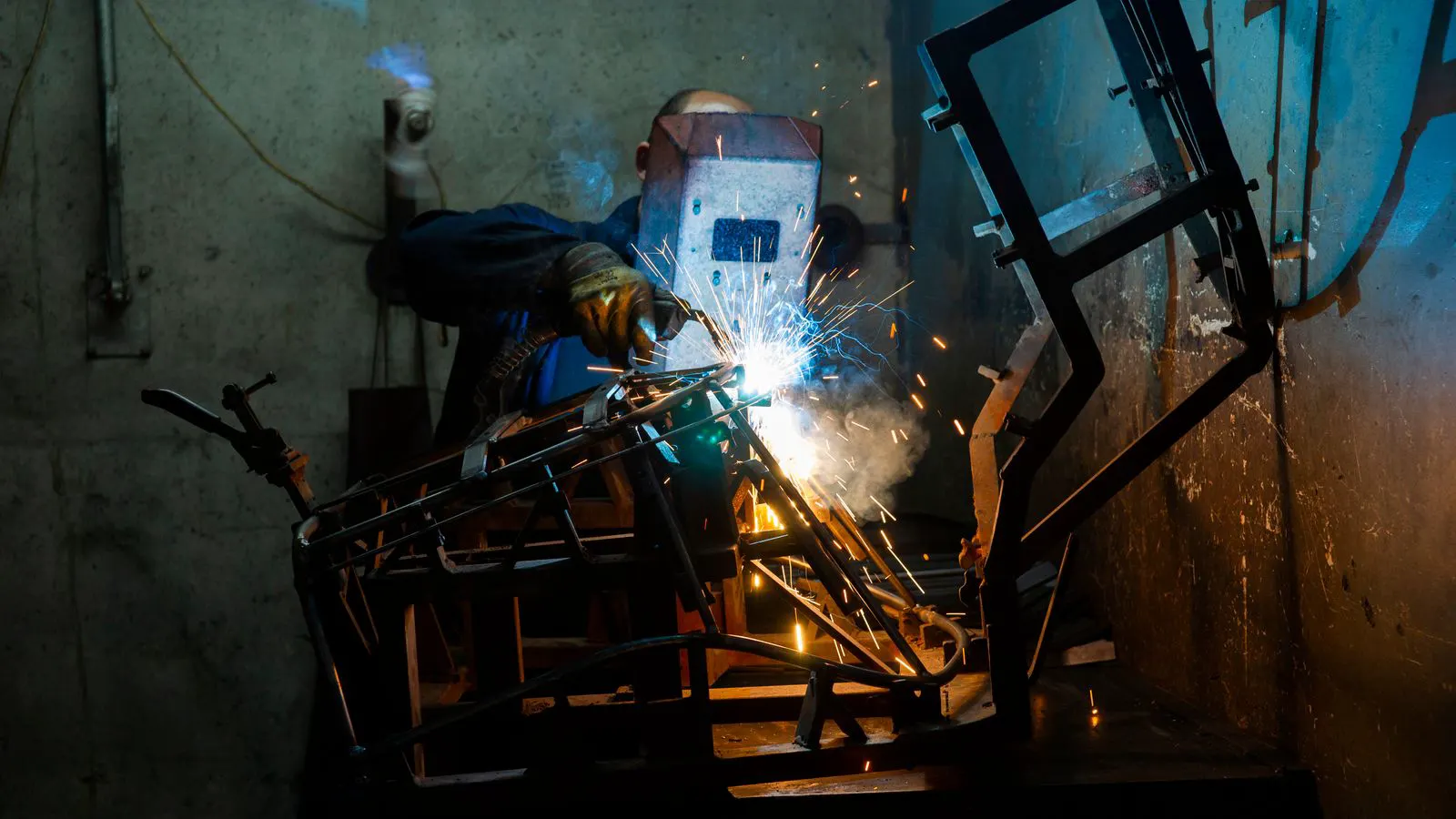 A production shop floor with MIG welding equipment and workstations.