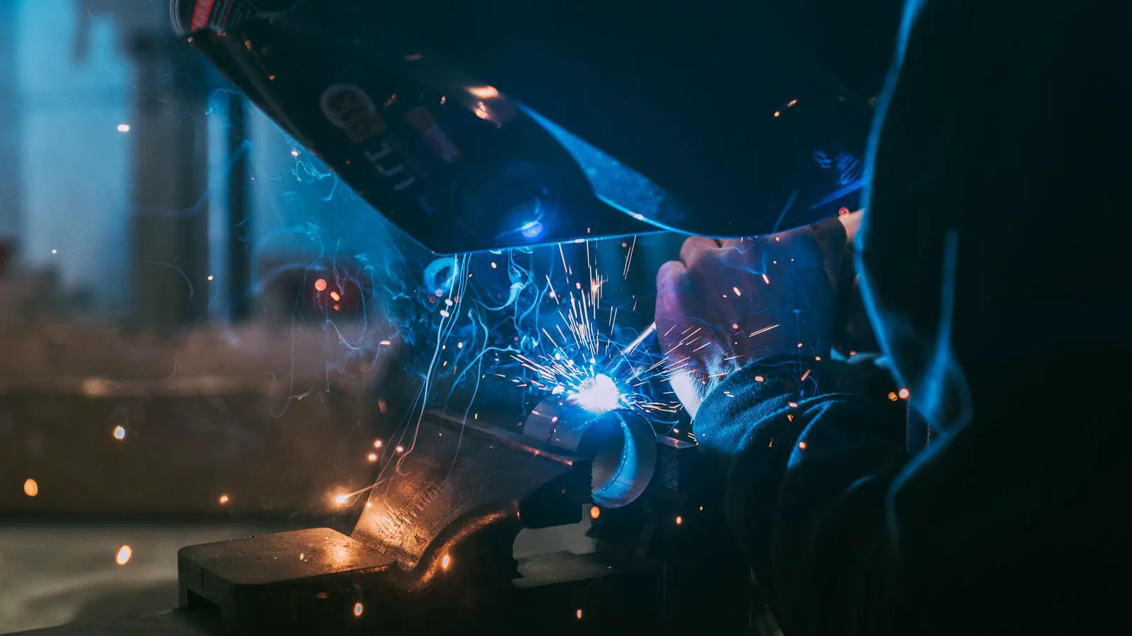 A worker inspecting a welding wire spool at a receiving station
