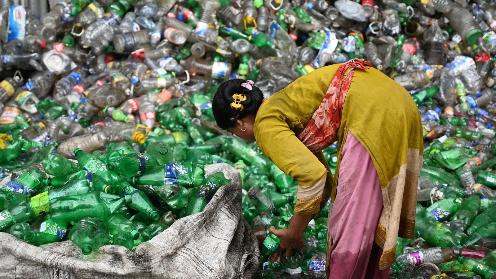A large optical sorter machine processing a stream of mixed plastic bales.