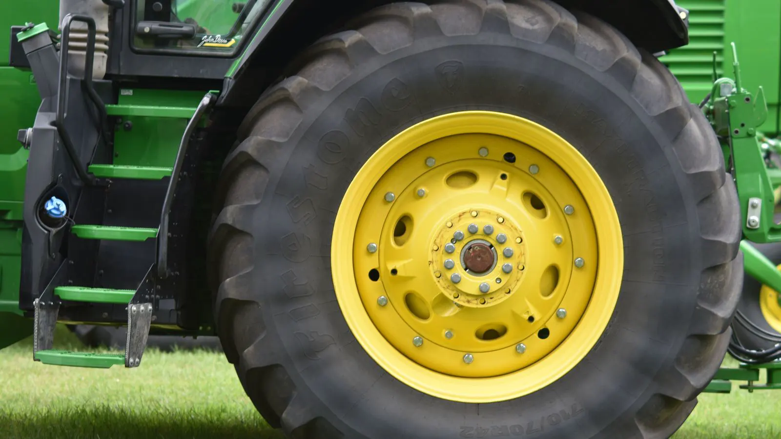 A farmer inspecting a tractor PTO shaft and clutch assembly.