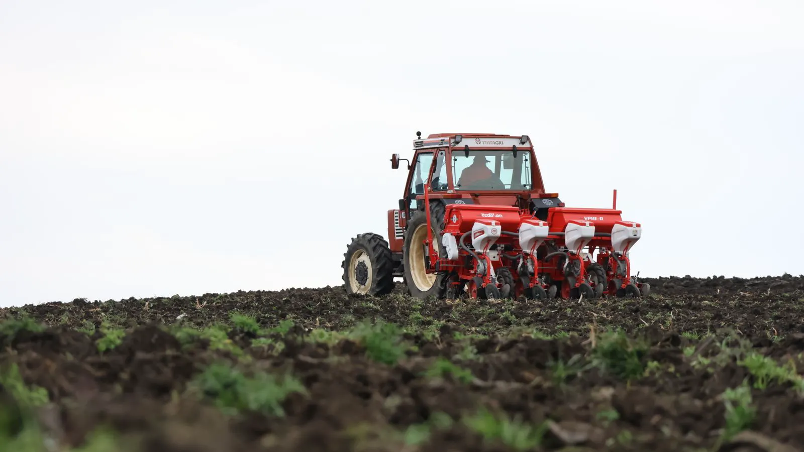 A modern planter moving through a field with uneven soil conditions.