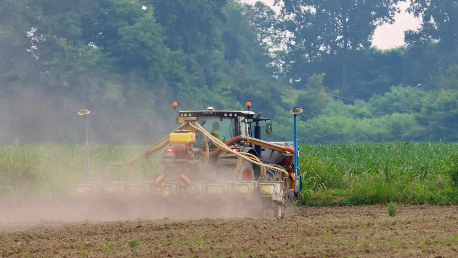 A tractor pulling an implement across a field with visible soil.