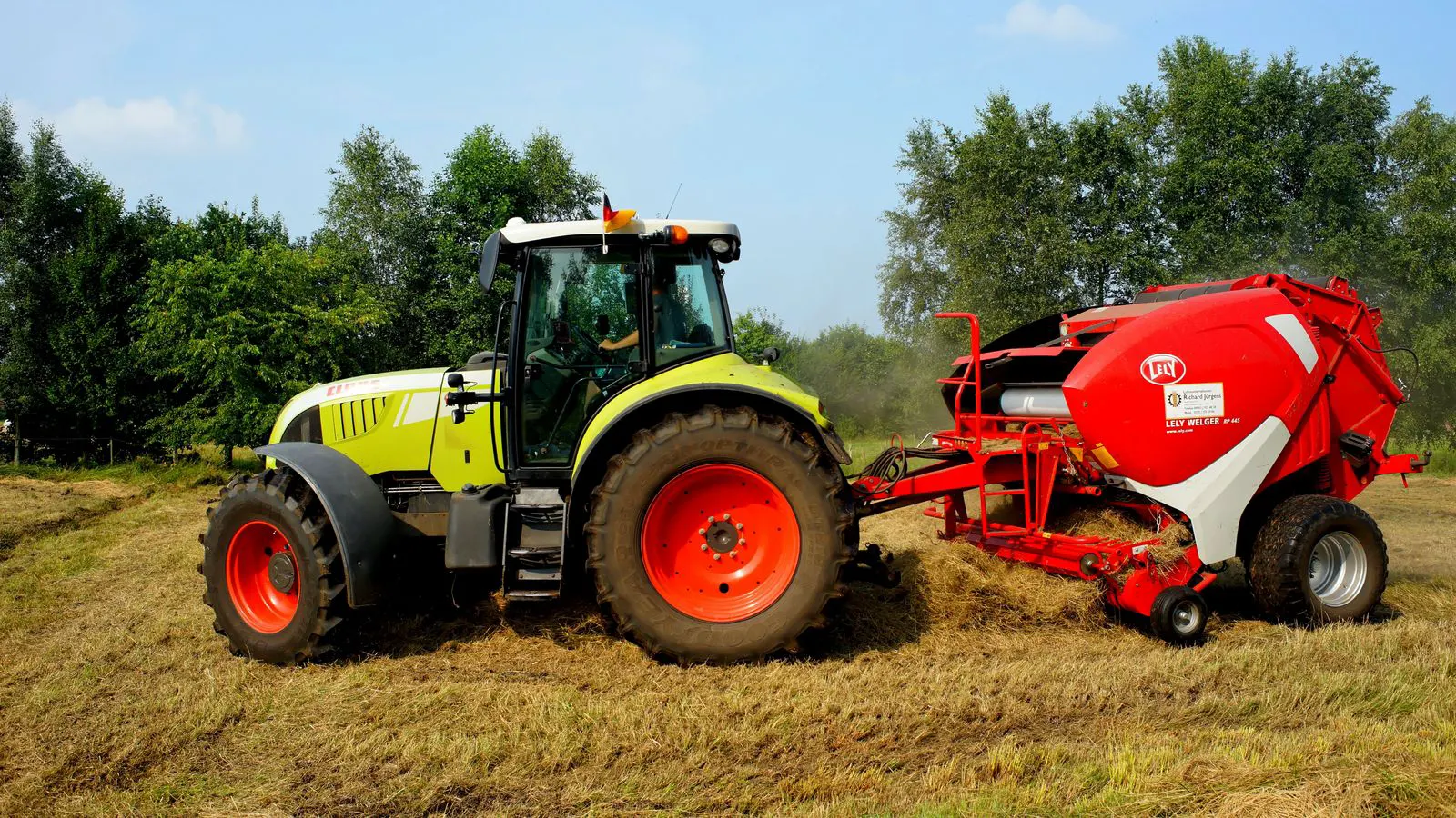 A red tractor with a visible hydraulic hose showing fluid drips on the ground.