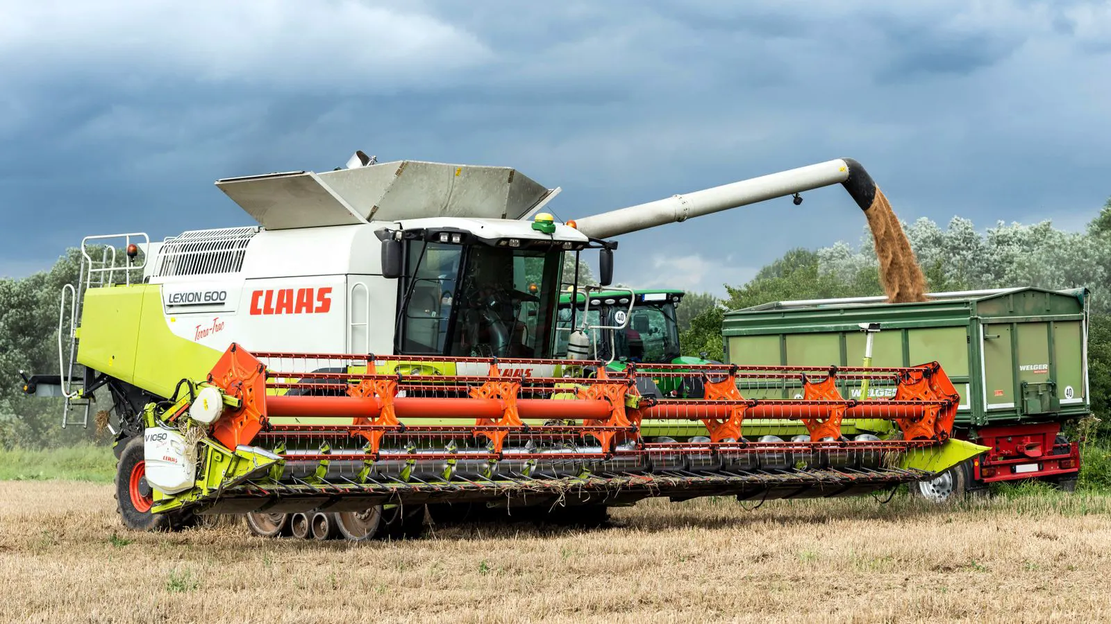 A large grain harvester moving through a harvested field