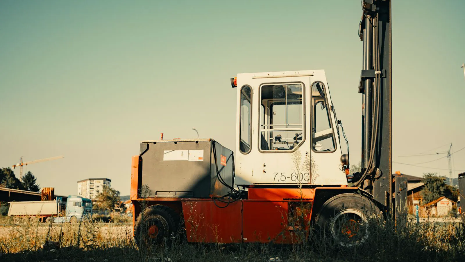 Side view of a diesel forklift and a gas powered forklift parked in a yard.
