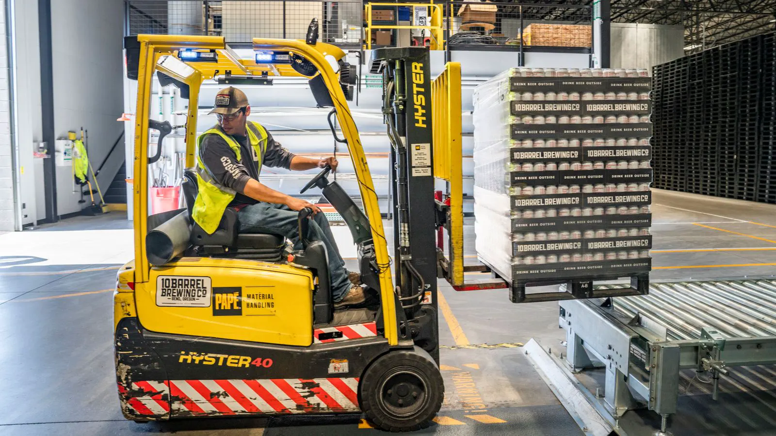 A forklift parked in a warehouse with financial charts visible in the background