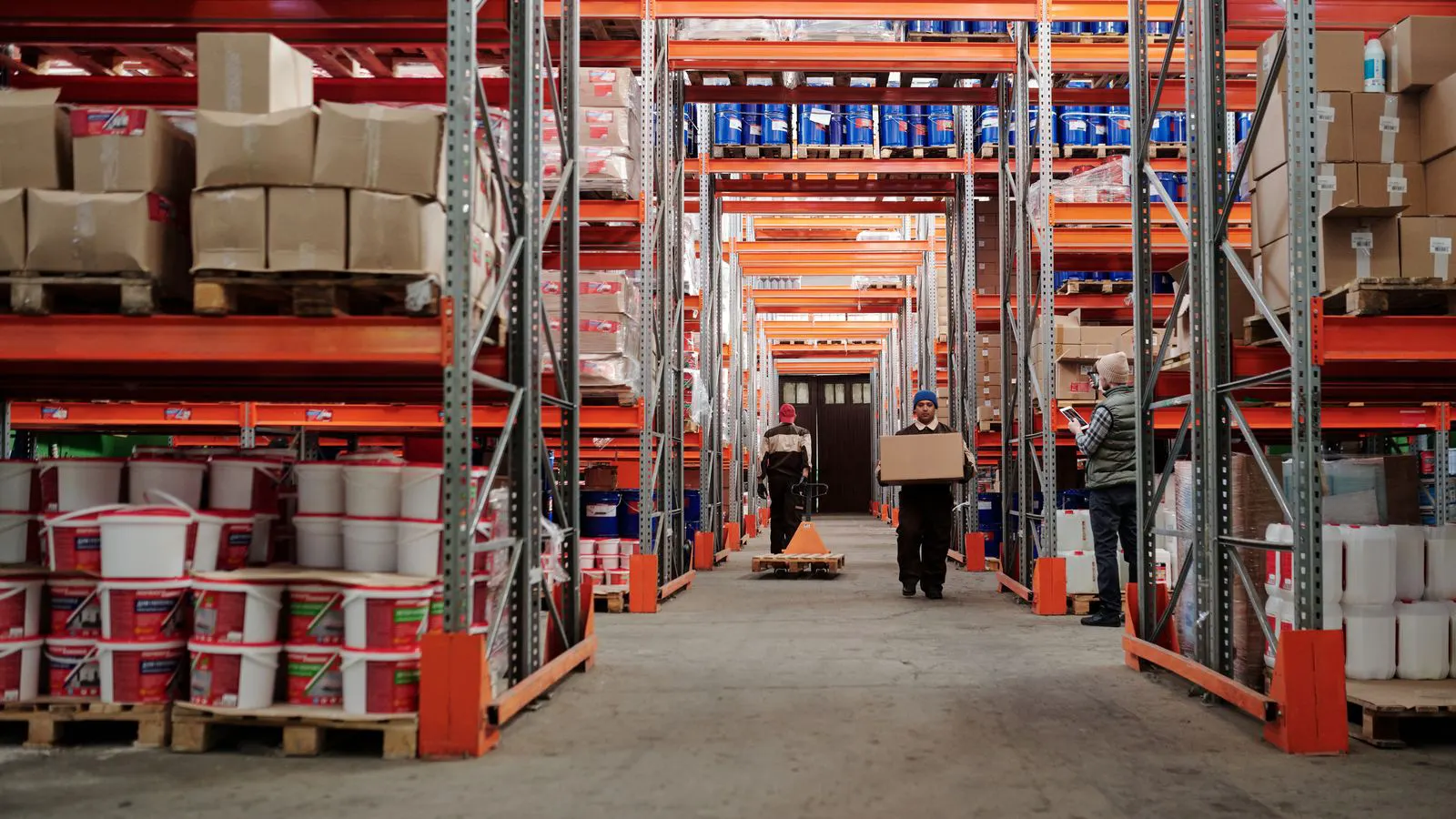A forklift reaches into tall racking in a narrow warehouse aisle