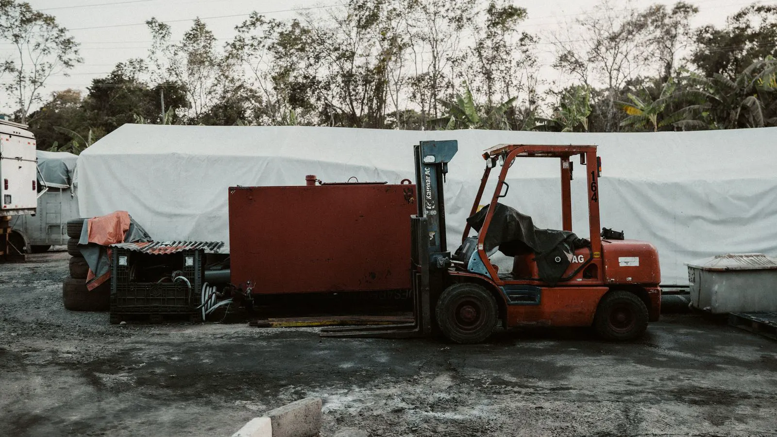 A forklift fitted with a pusher attachment near a loading dock