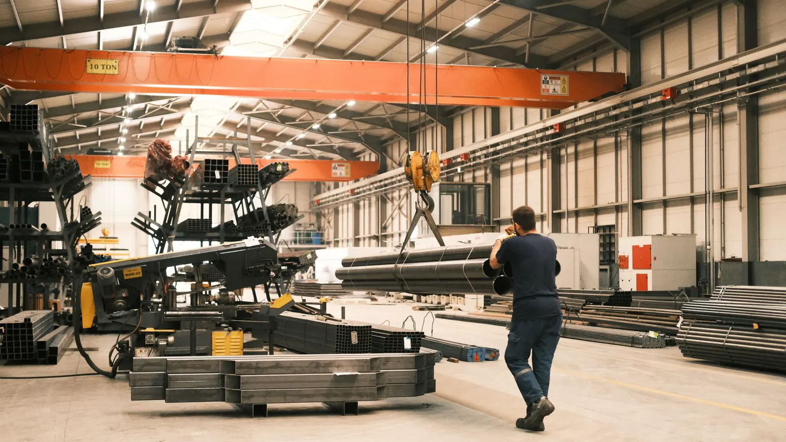 A heavy duty chain hoist suspended from a factory ceiling beam.
