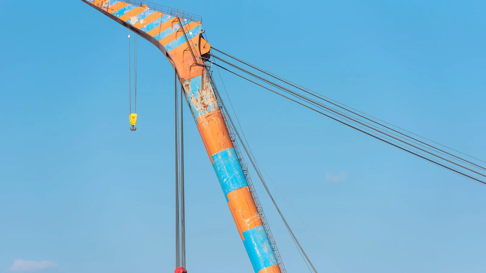 Workers inspecting a steel wire rope hoist on a factory assembly line.