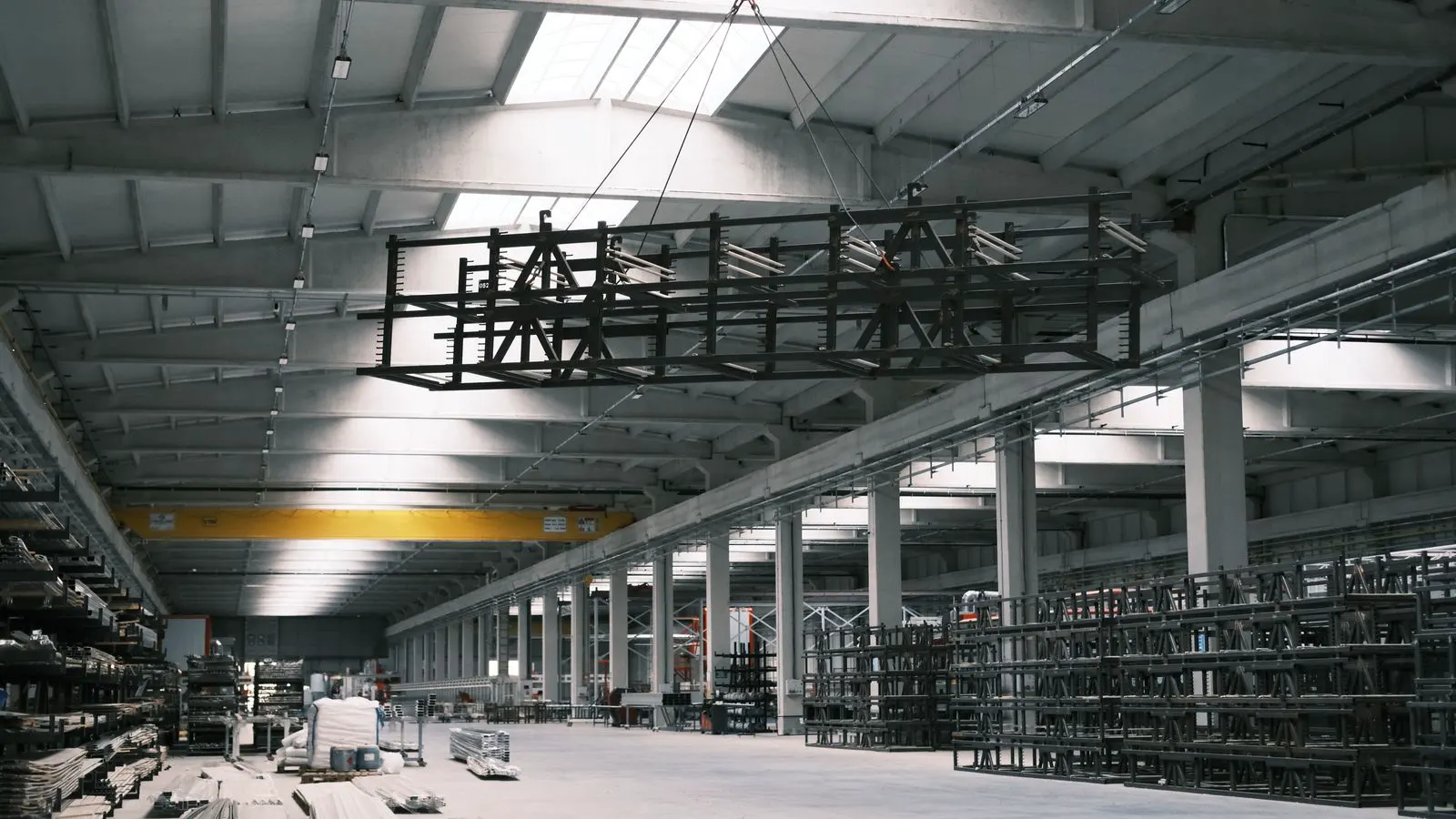 A large industrial crane suspended from warehouse ceiling beams