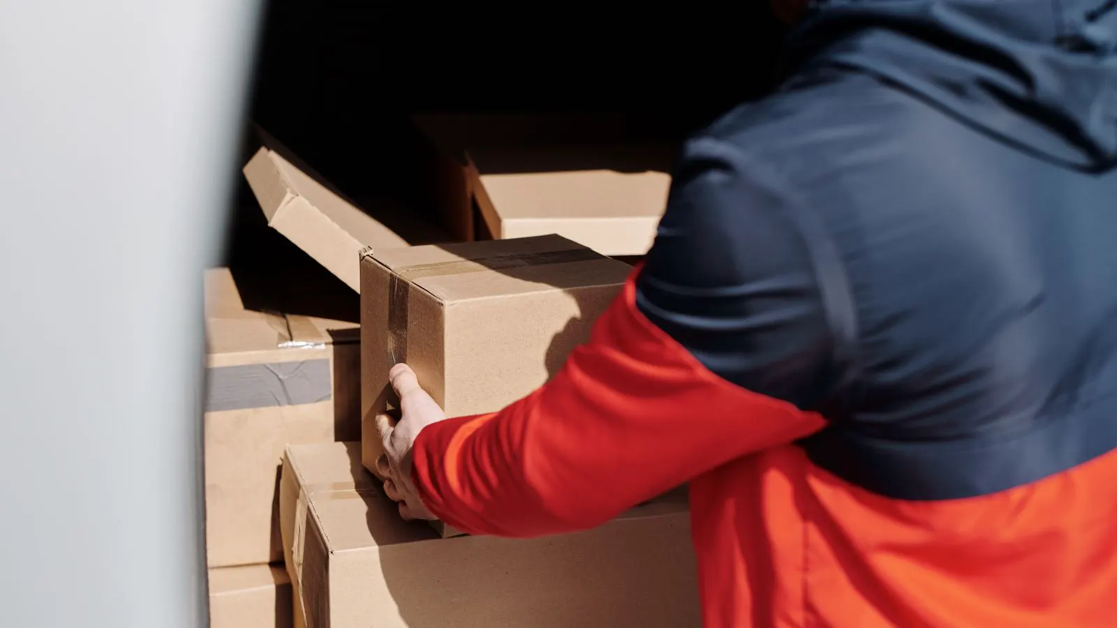 A robotic arm holding a cardboard box with a parallel gripper mechanism