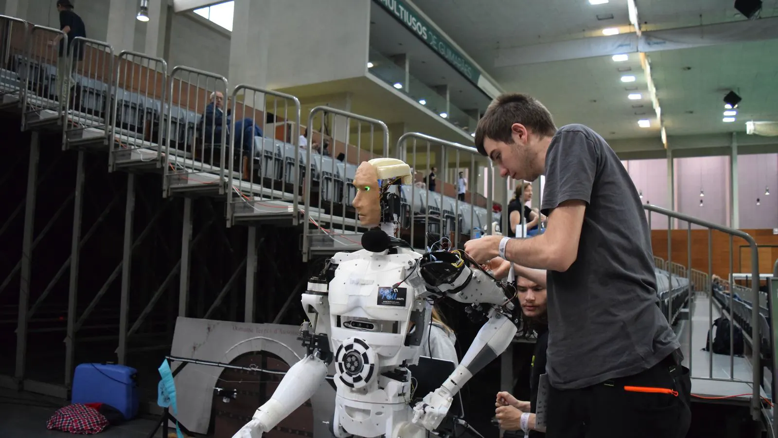 A technician inspecting the arm of an industrial robot on a factory floor