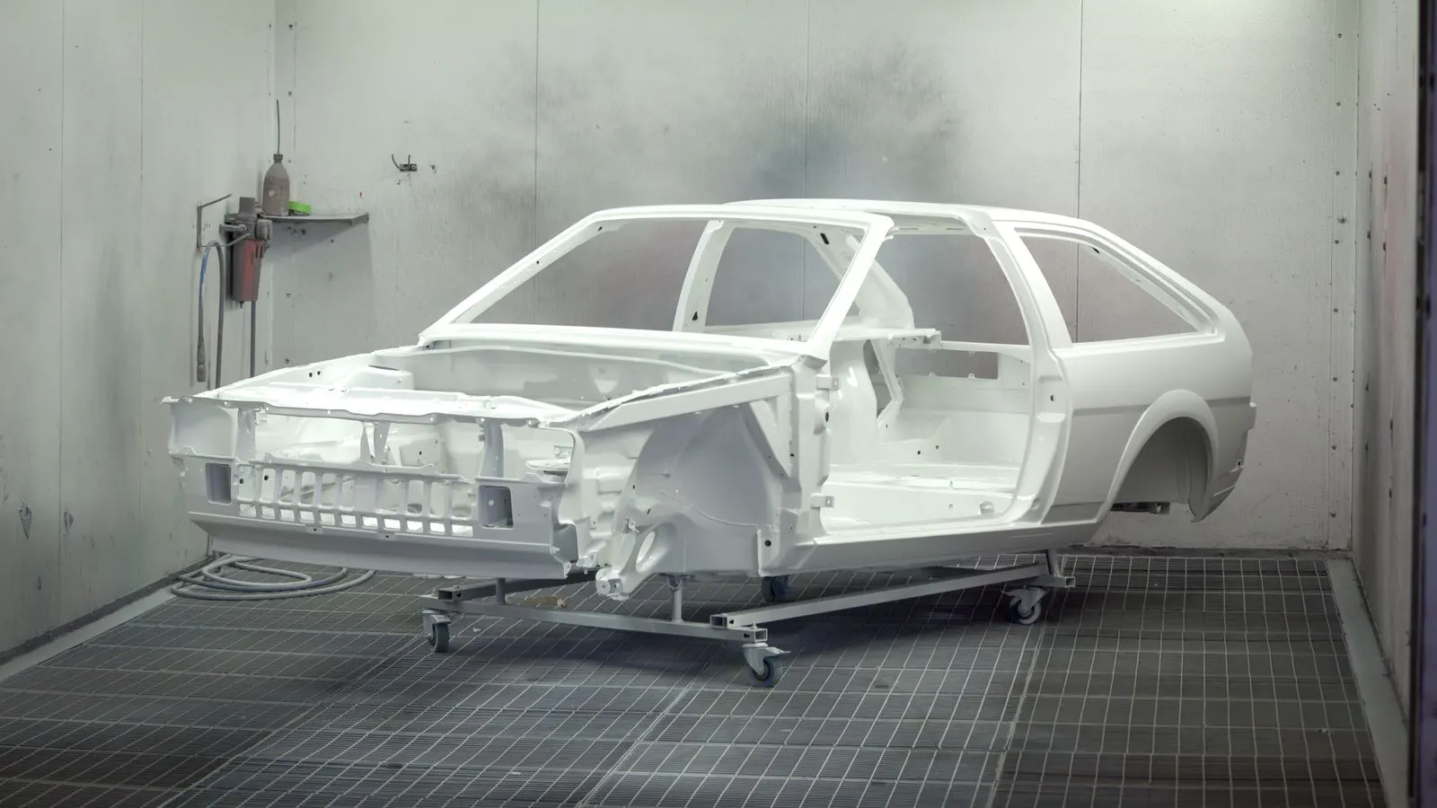 A powder coating booth with a metal part suspended for coating application