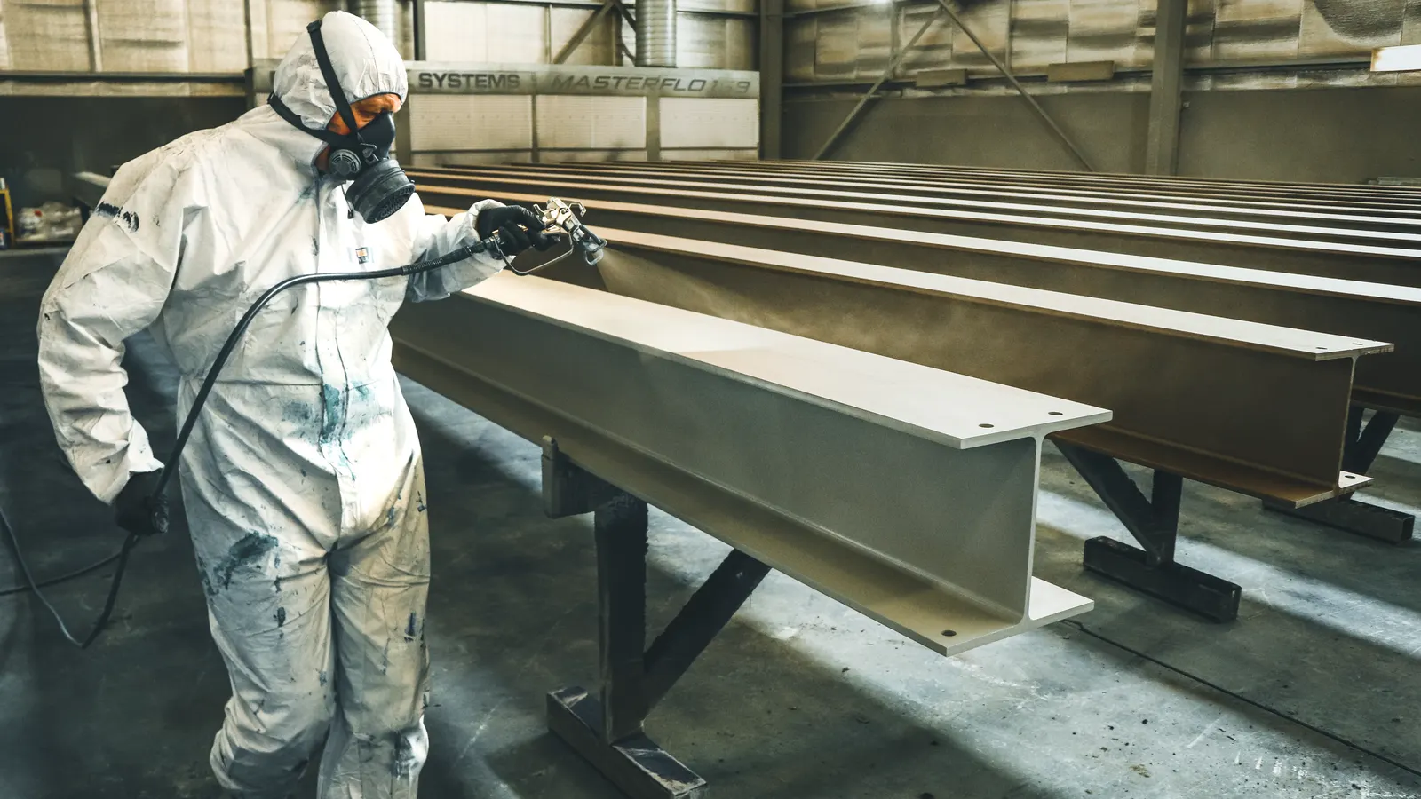 A powder coating spray gun applying a coating to a metal part inside an oven.