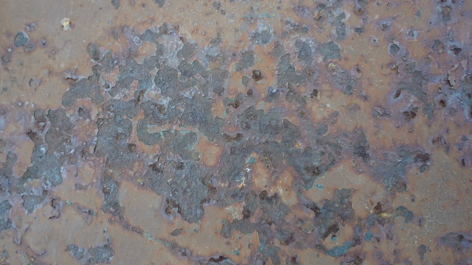 A close view of a steel plate showing rust patches after abrasive cleaning.