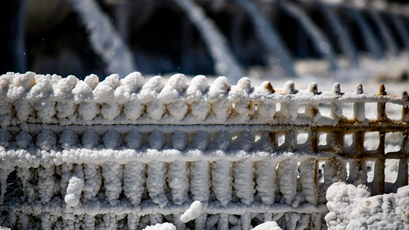 Metal components suspended inside a fog-filled salt spray chamber.