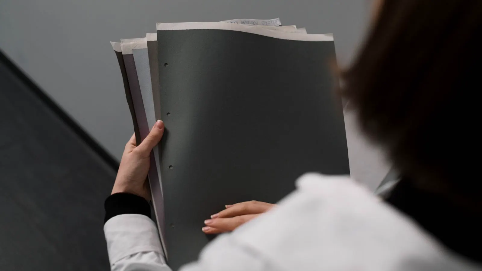 A technician reviews a stack of metal parts and a printed quotation sheet at a workbench.