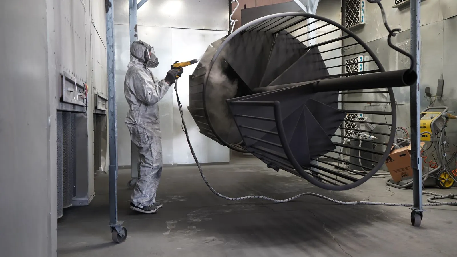 A metal part coated in dry powder inside a curing oven.