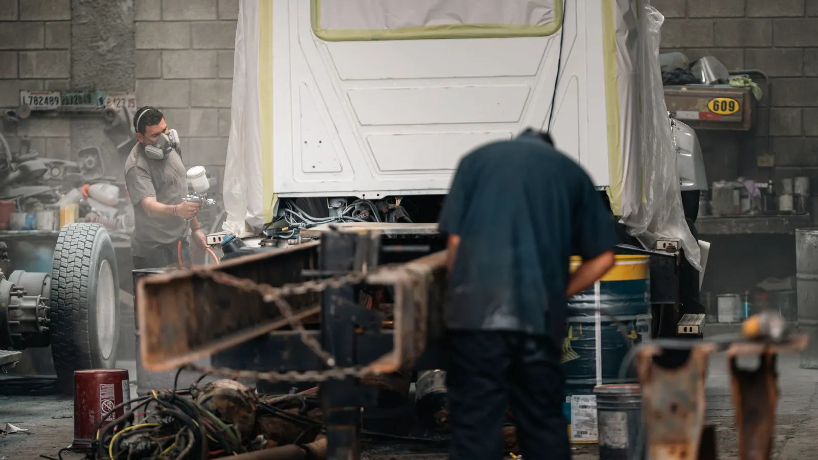 A professional operator applies liquid coating to a metal part.