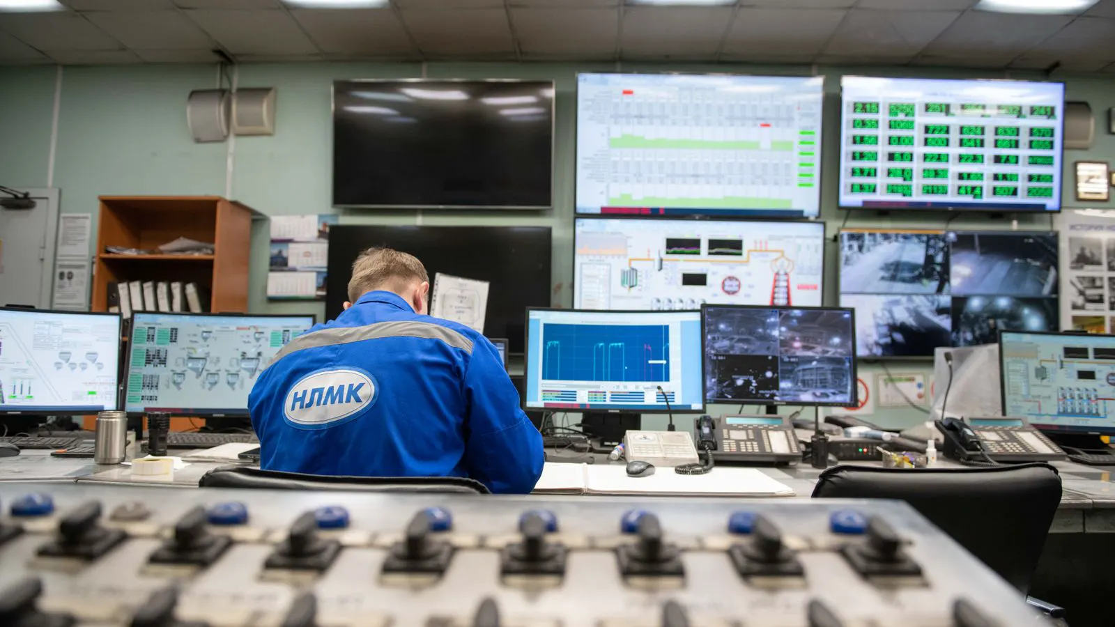 Large wall displays showing factory data in a control room