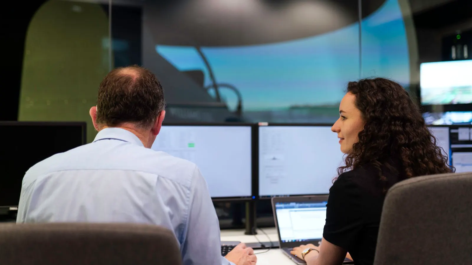 Engineers reviewing system status on a factory control room screen.