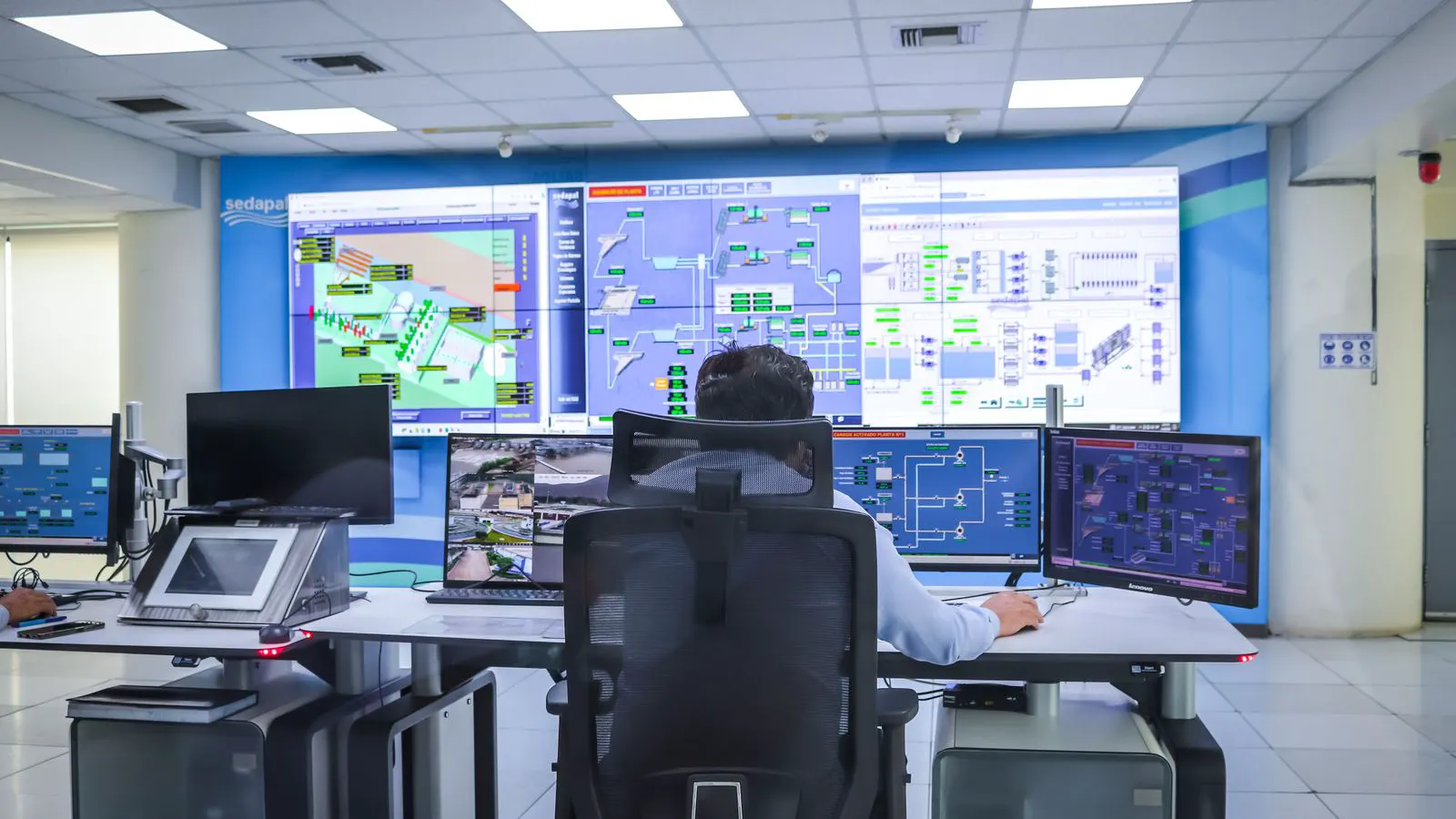 Large wall-mounted screen showing factory monitoring dashboards