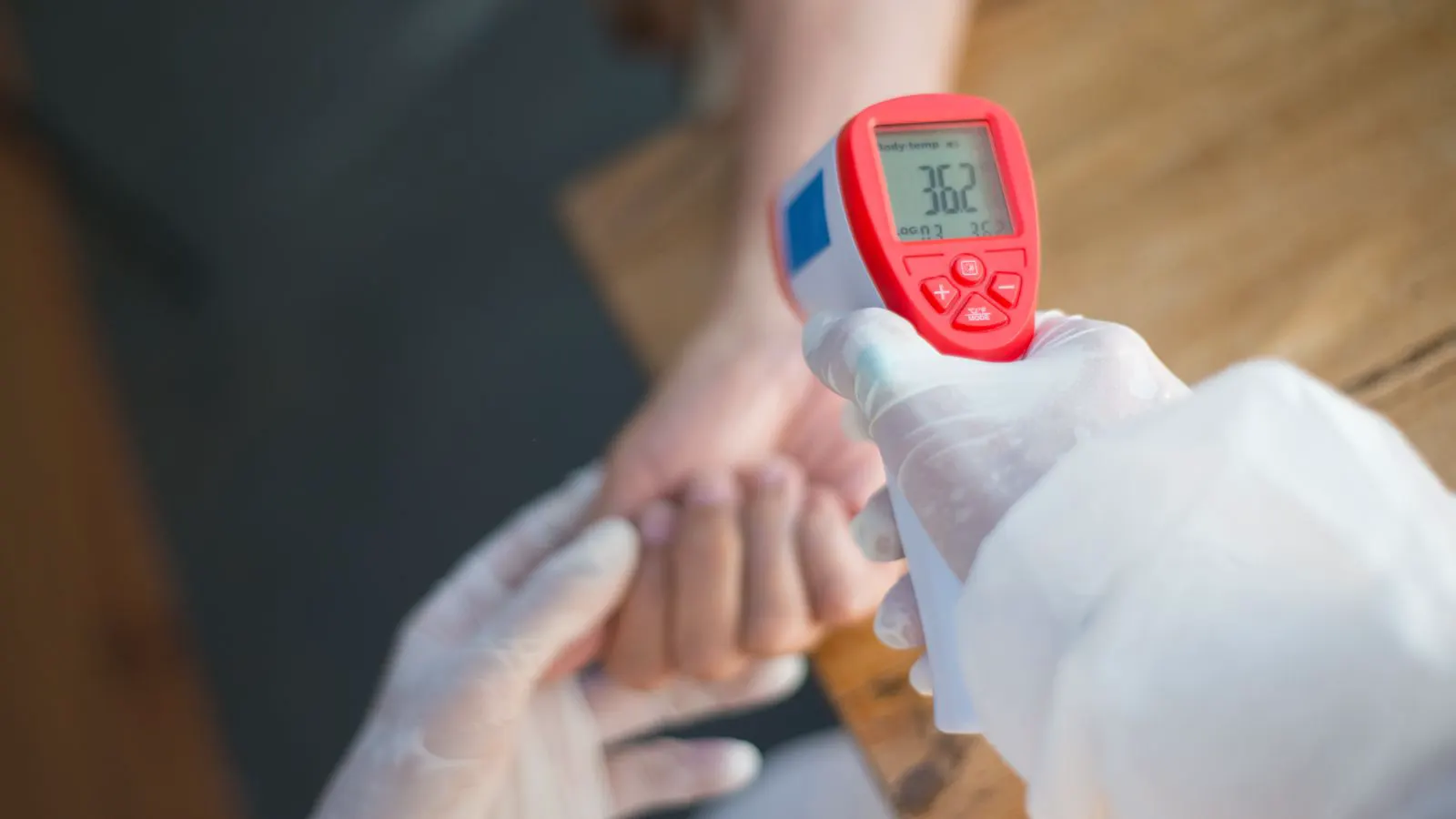 A close-up of a handheld infrared thermometer pointed at a machine part.