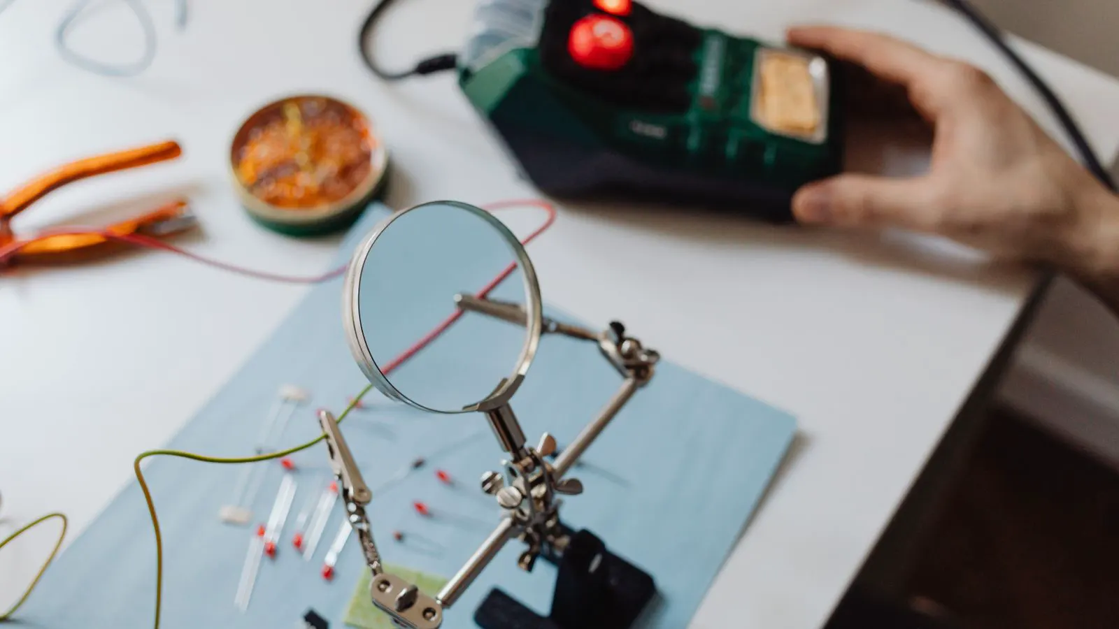A worker applies heat to a wire terminal on a metal board