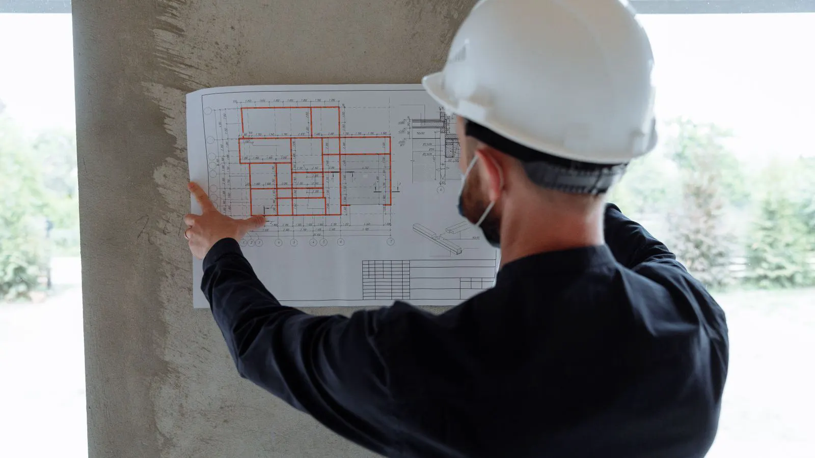 An engineer checks printed switchgear drawings on a desk.