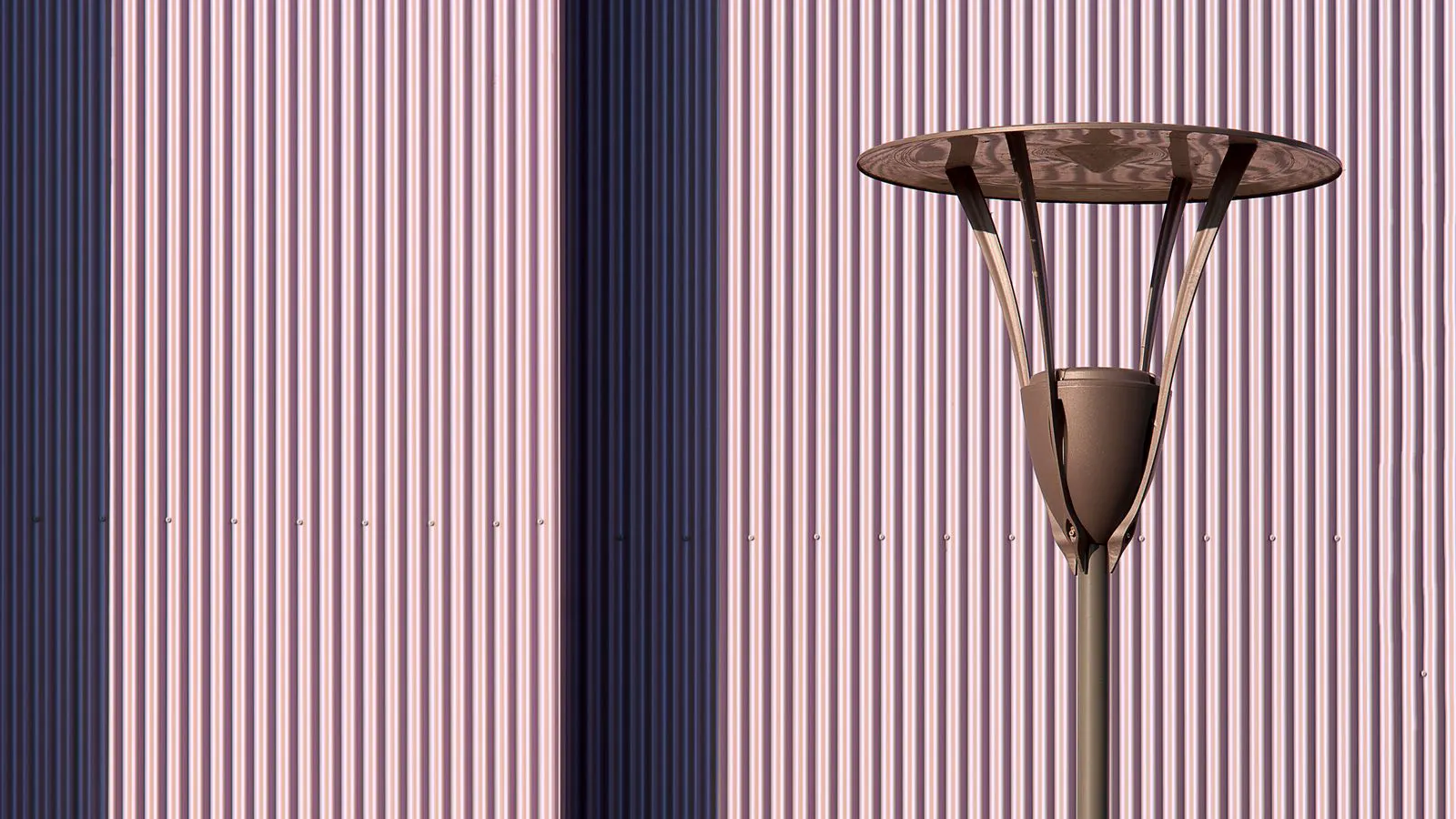 A modern LED street light fixture mounted on a metal pole at dusk