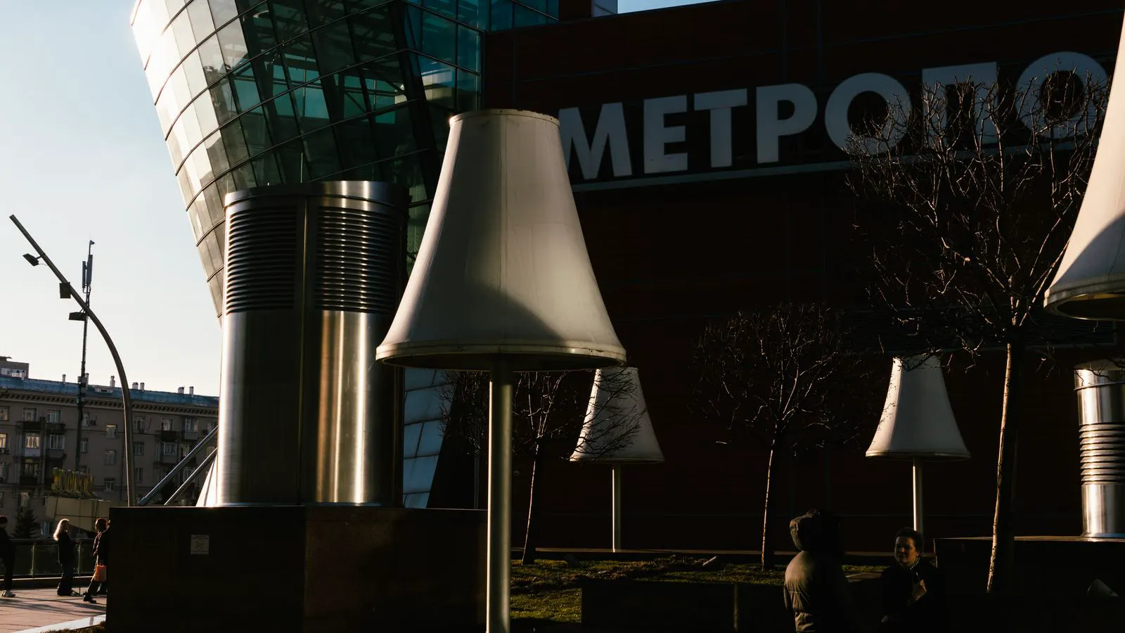 A modern LED street lamp illuminates a quiet city street at dusk.