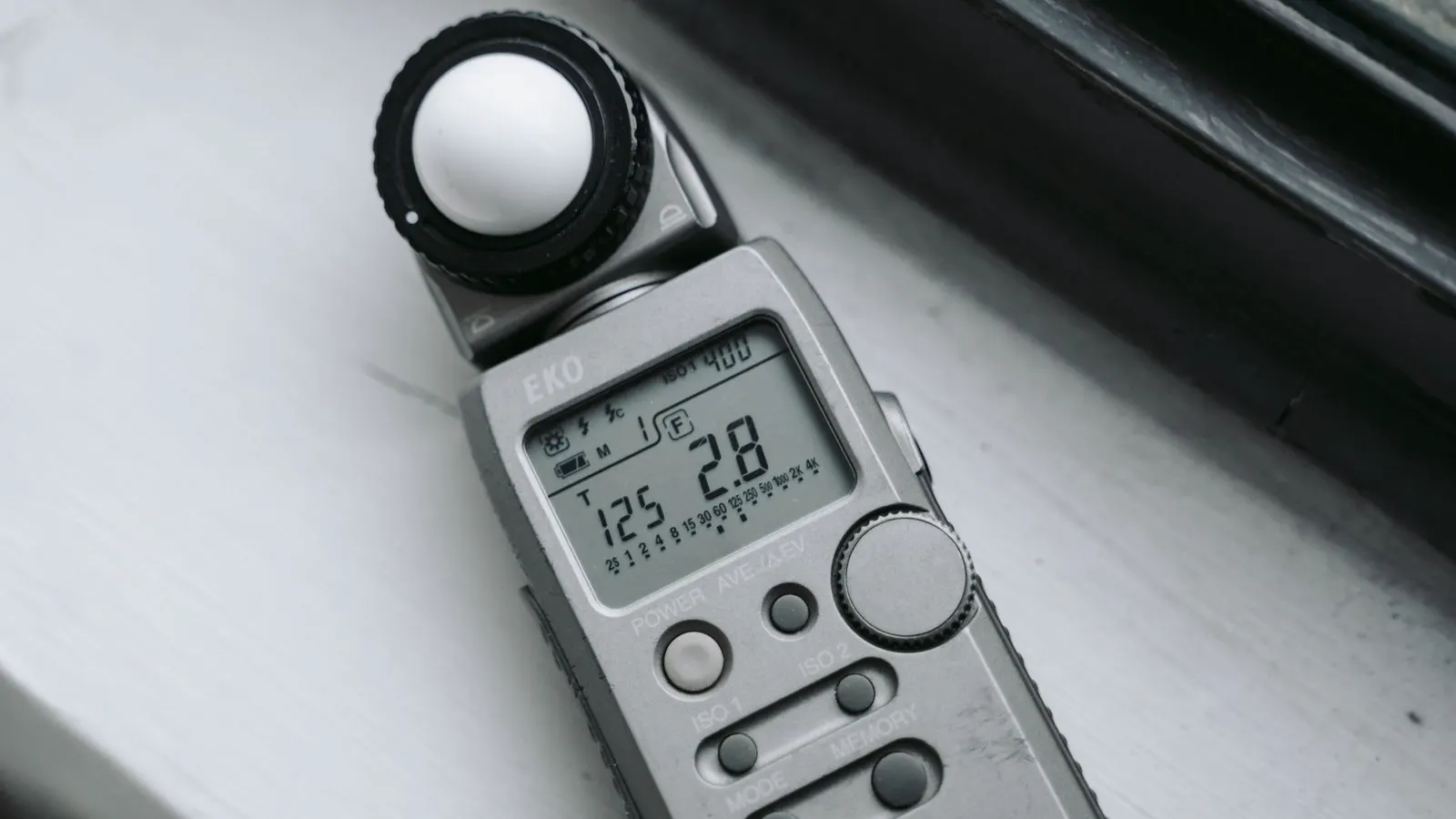 A digital power meter displaying wattage readings next to a large indoor LED screen.
