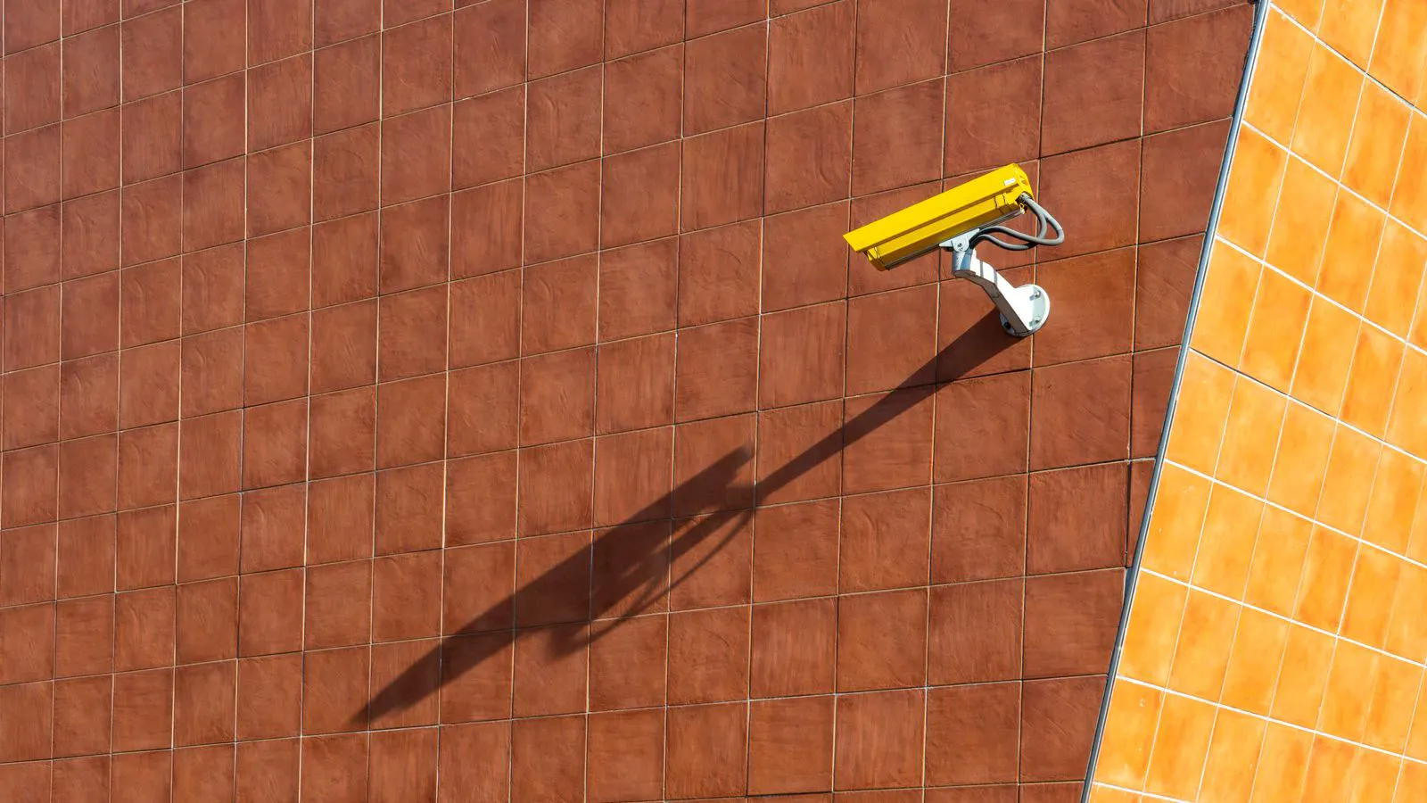 A modern IP camera mounted on an exterior wall corner
