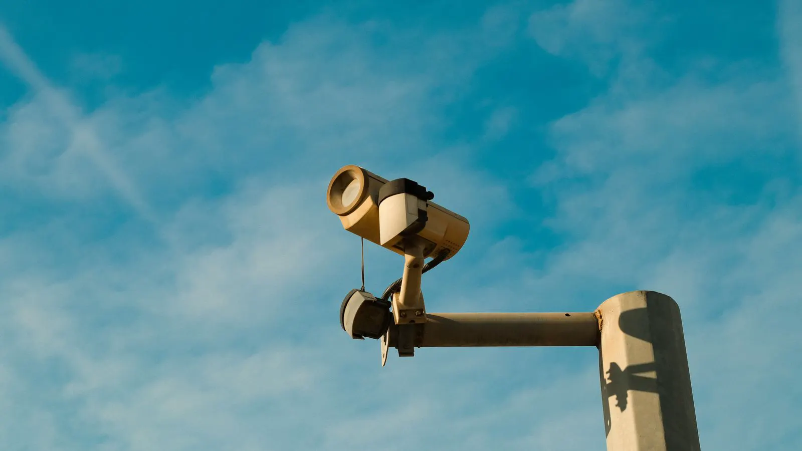 A technician inspecting a metal camera pole during a site survey.