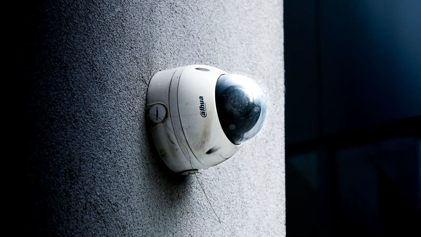 A white dome IP camera mounted on a concrete wall