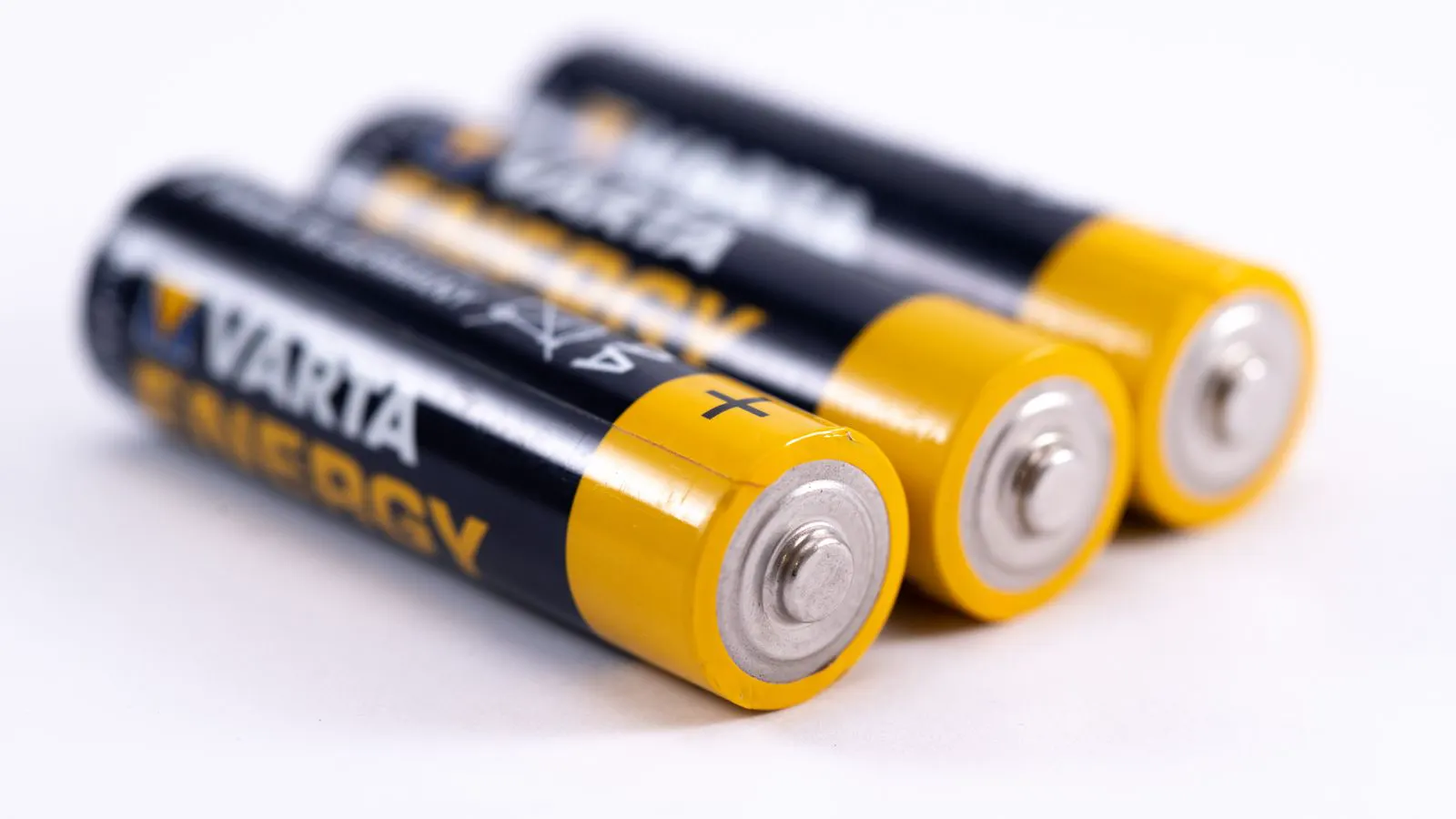 An engineer examines battery cells with a digital caliper and notebook