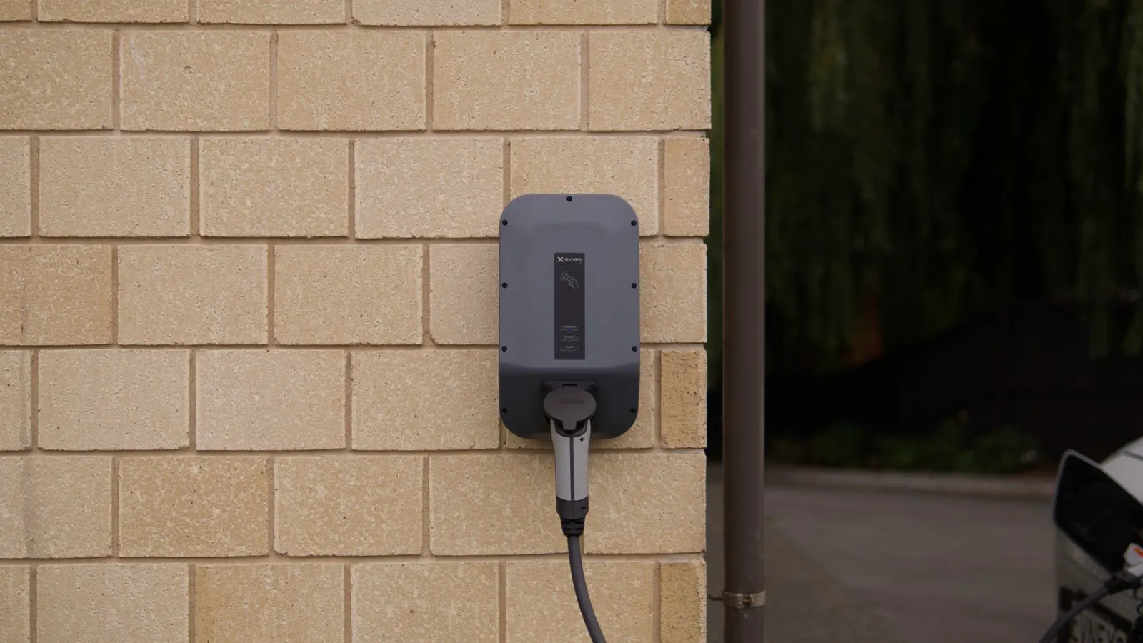 A white wall mounted unit with a black cable hanging from the side