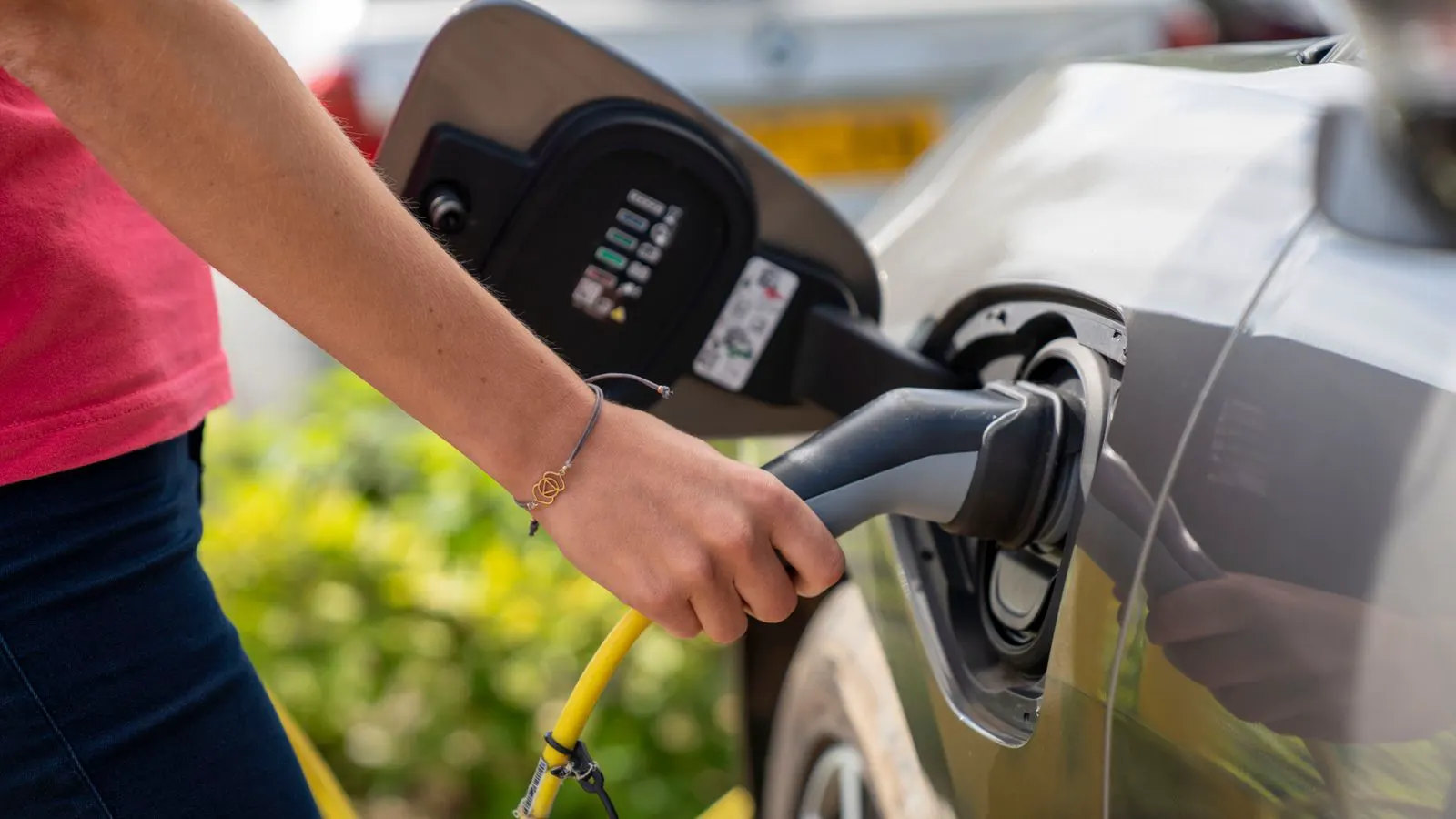 A white wall-mounted EV charging unit with a black cable coiled around it.