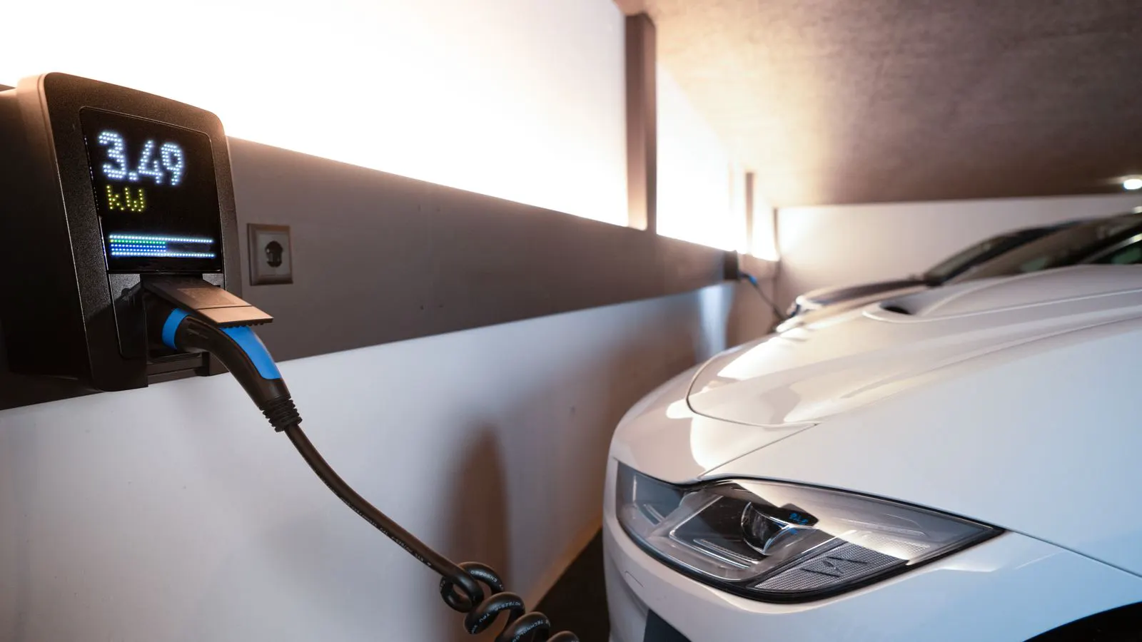 A white EV charging unit with a CE label on a concrete wall