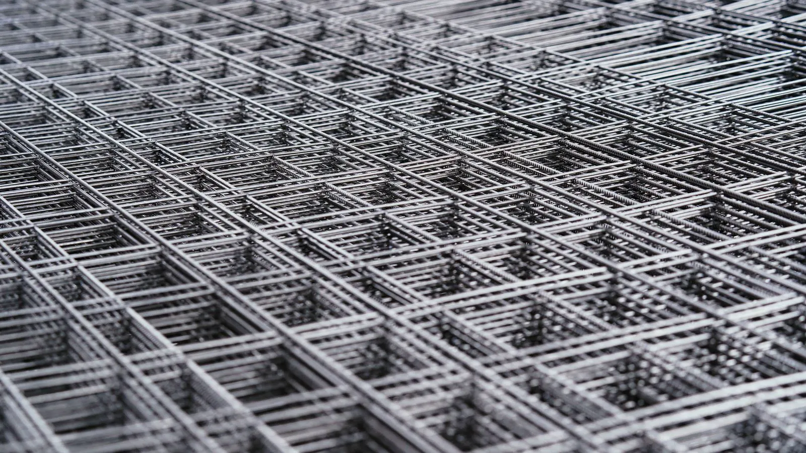 A worker holding a spool of steel wire near a concrete pour