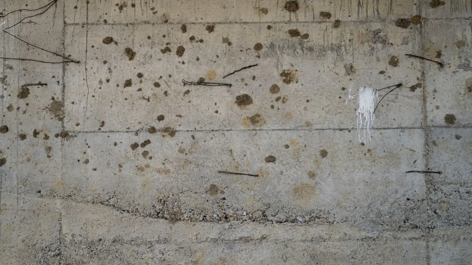 Exposed corroded steel bars protruding from a cracked concrete wall