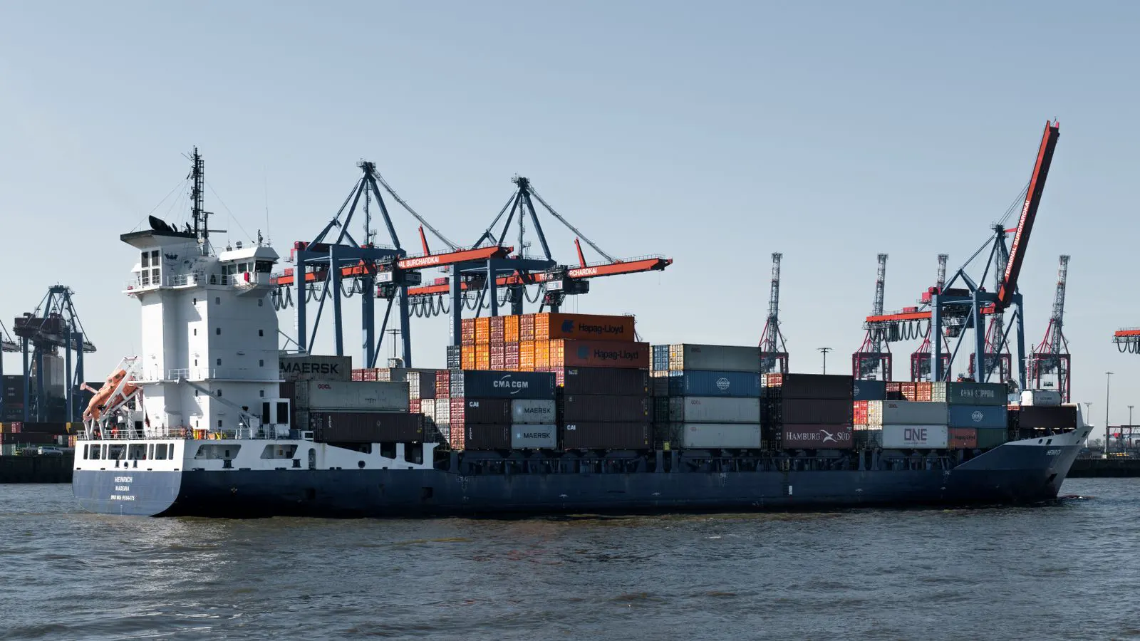 A cargo ship loading containers of industrial polymer material at a port.